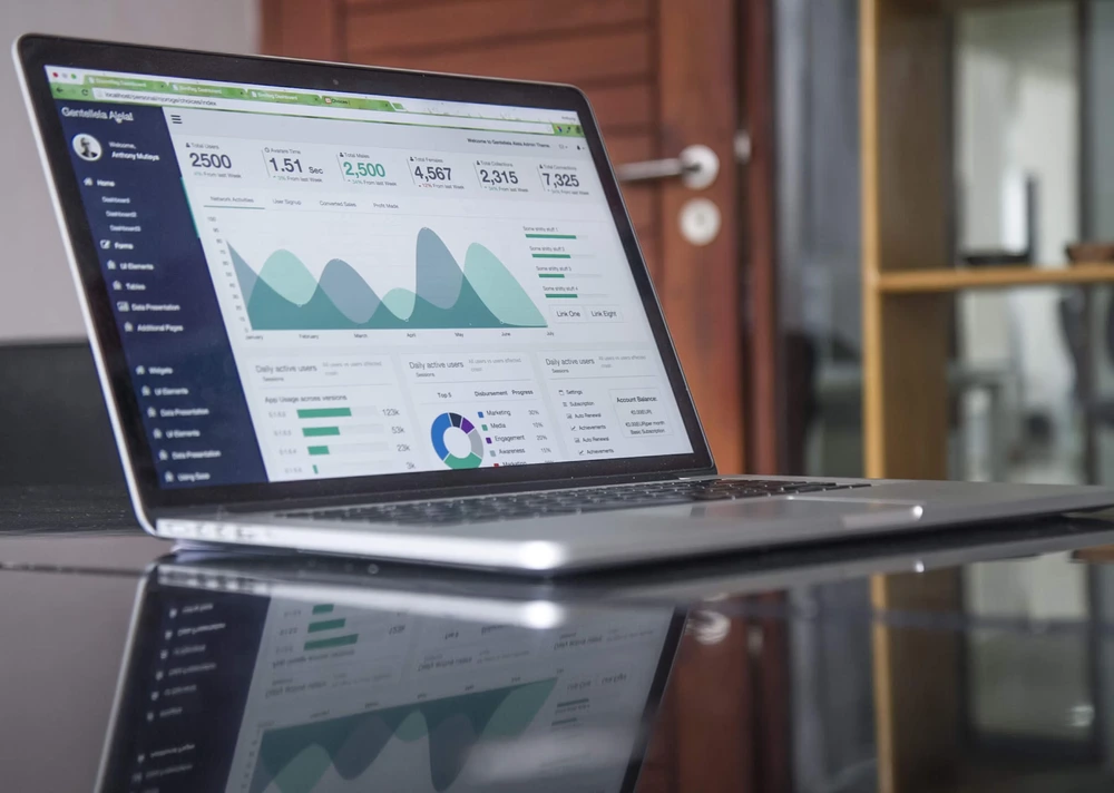 Silver laptop open on a desk, screen displaying analytical charts and graphs